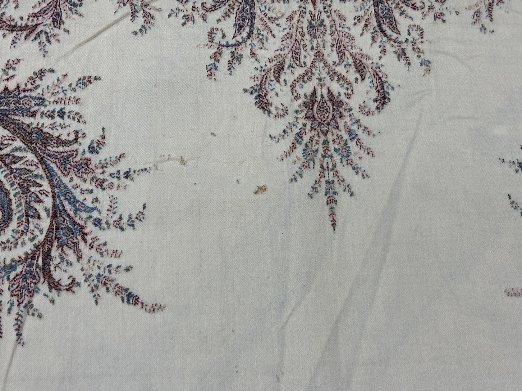 A late 19th century wool woven Paisley shawl with cream central cartouche (some damage)